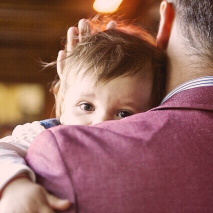 Un petit enfant dans les bras de son père.